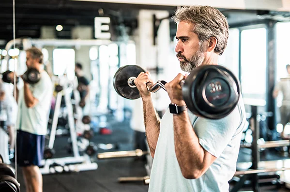 Fit middle-aged man training with dumbbells
